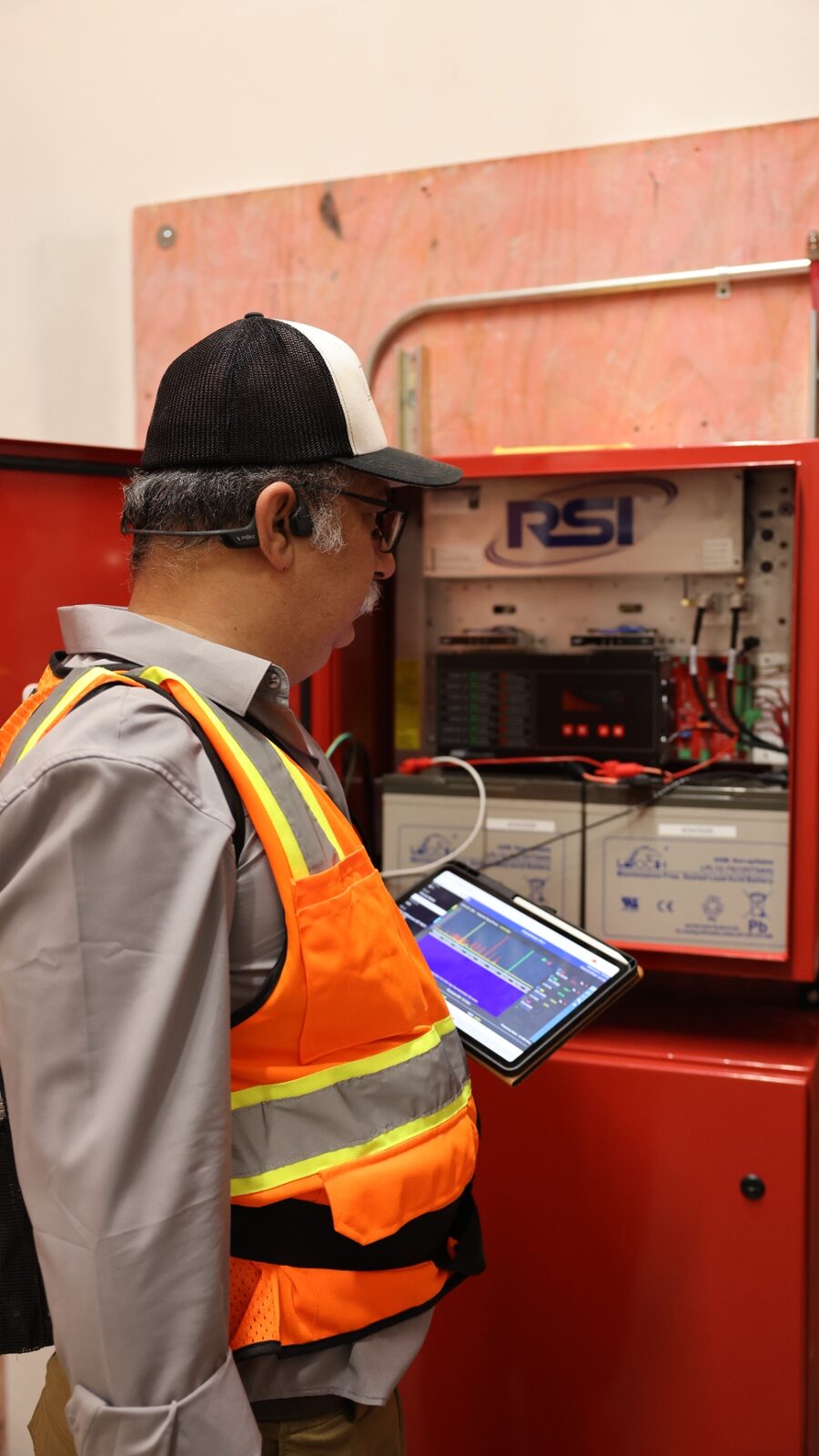 Zion technician commissioning an RSI public-safety BDA — spectrum analyzer running on tablet, RSI cabinet open